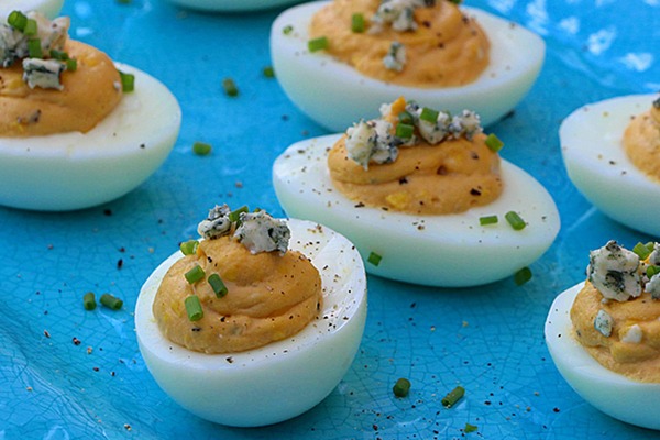 buffalo deviled eggs plated with blue cheese and chive garnish