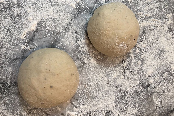 pizza dough balls on flour dusted counter
