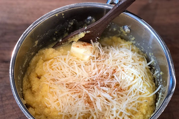 adding butter, cheese, and seasonings to cooked polenta