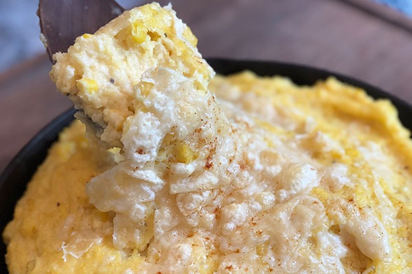 spicy sweet corn polenta with cheese on top in cast iron pan