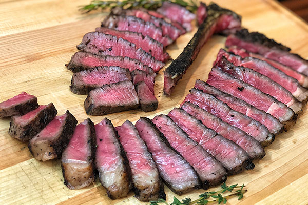 sliced T-bone steak on board