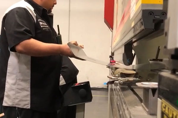 worker bending steel sheets with a machine at lynx grills factory