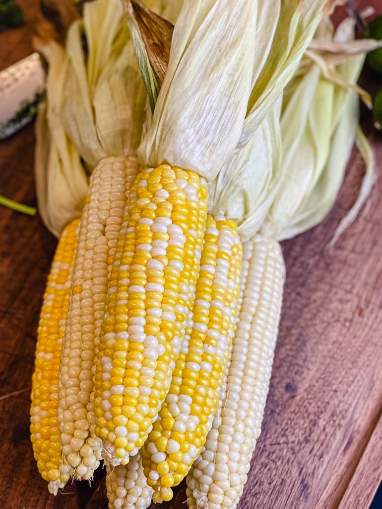 fresh corn on the cob sitting on a cutting board