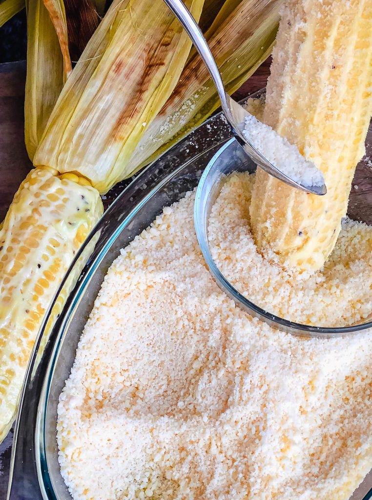 cotija cheese being applied to Mexican street corn