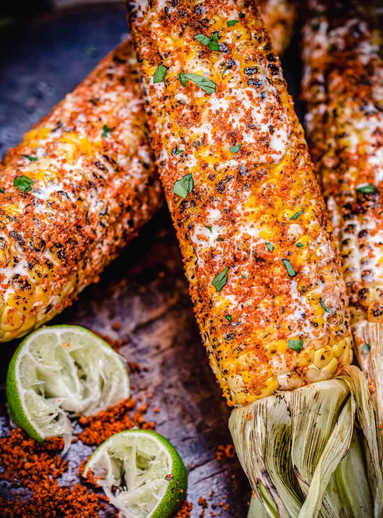 heavily seasoned Mexican street corn with lime wedges