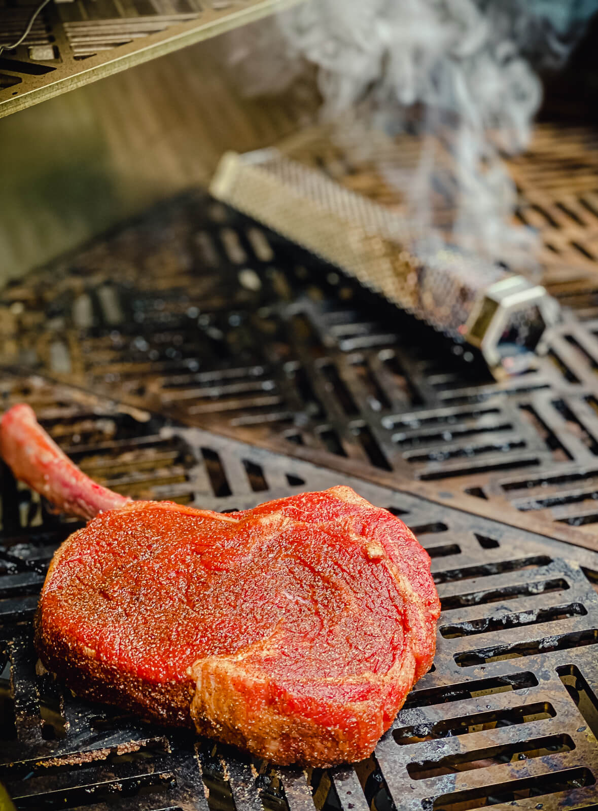 tomahawk ribeye placed on gas grill with smoker tube