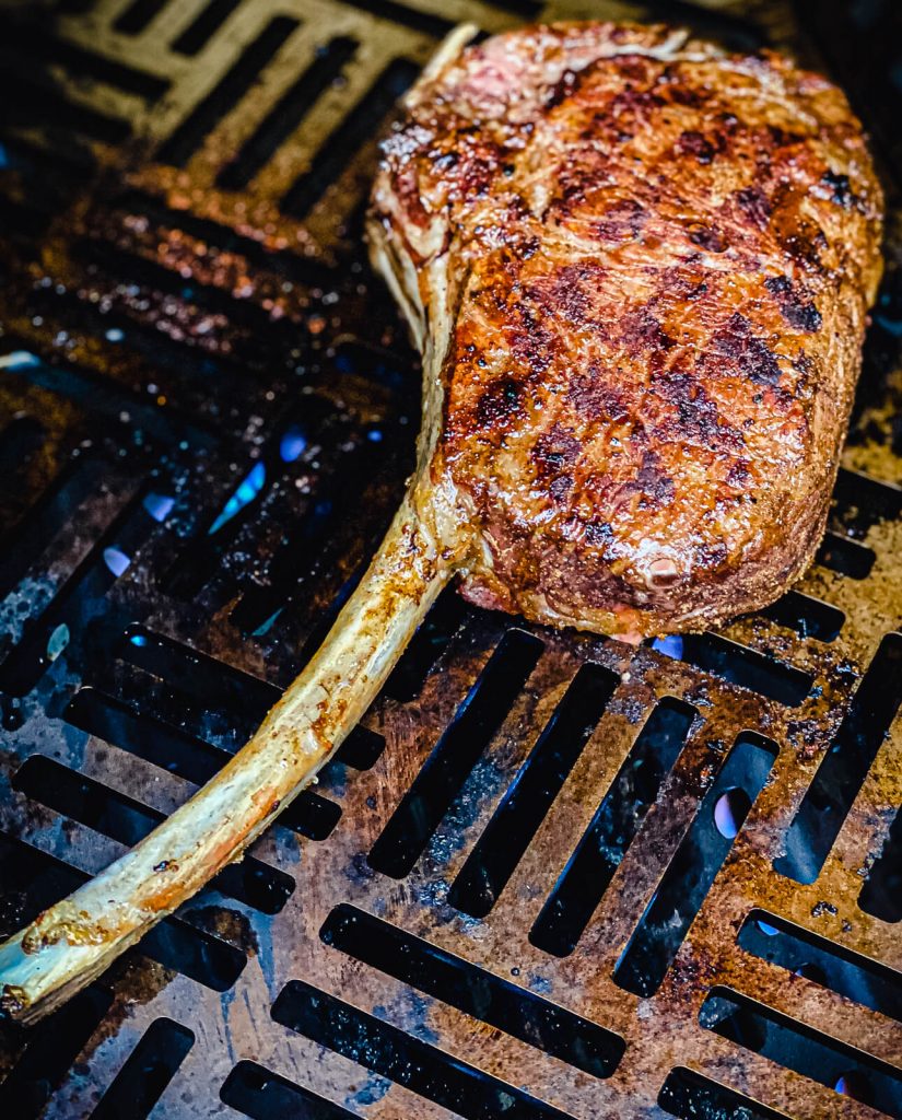 tomahawk ribeye being seared on a gas grill