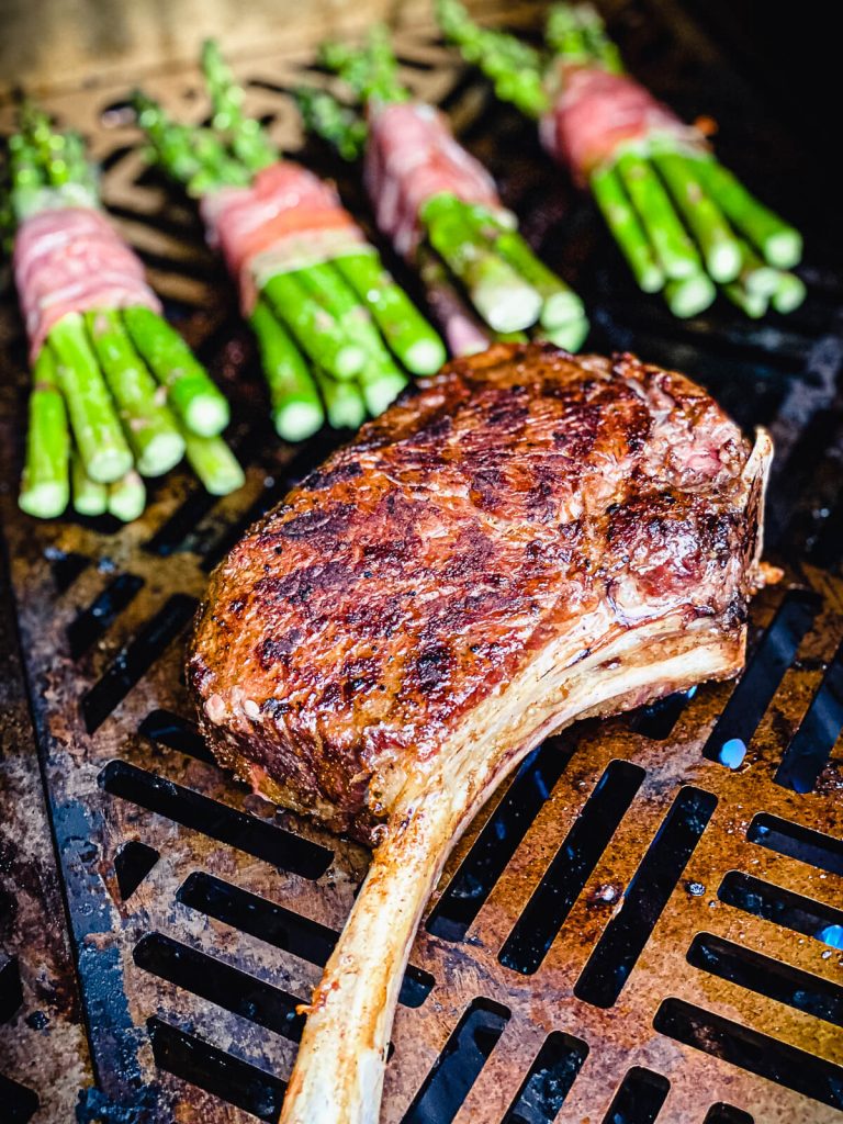 tomahawk steak on a gas grill with asparagus