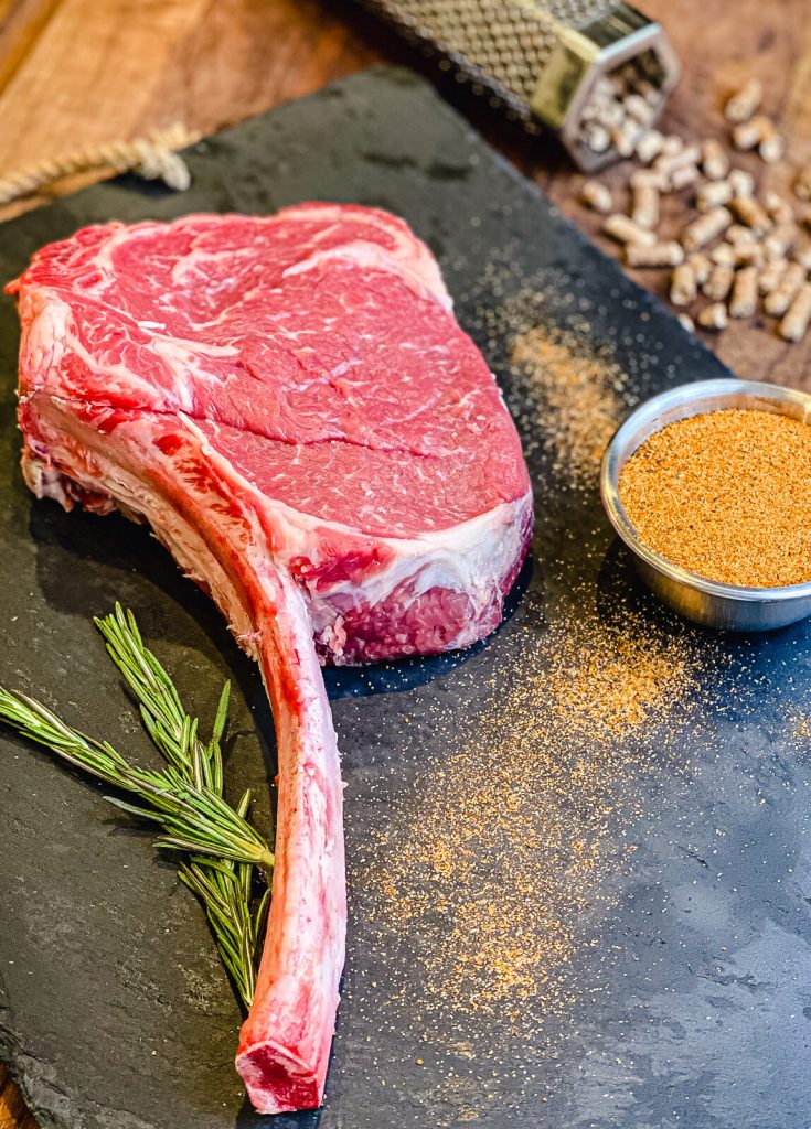 uncooked tomahawk ribeye on slate tray