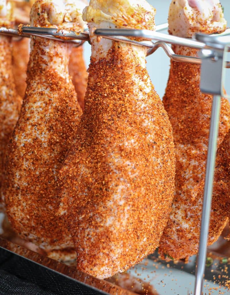 chicken legs hanging in a rack, ready to be put on the smoker