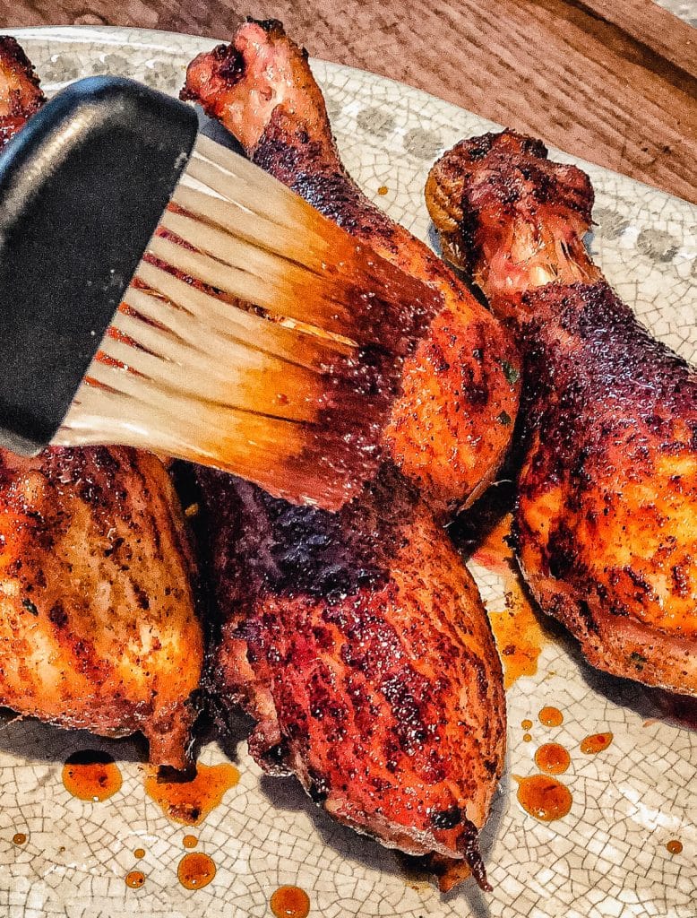 smoked chicken drumsticks being glazed with honey glaze