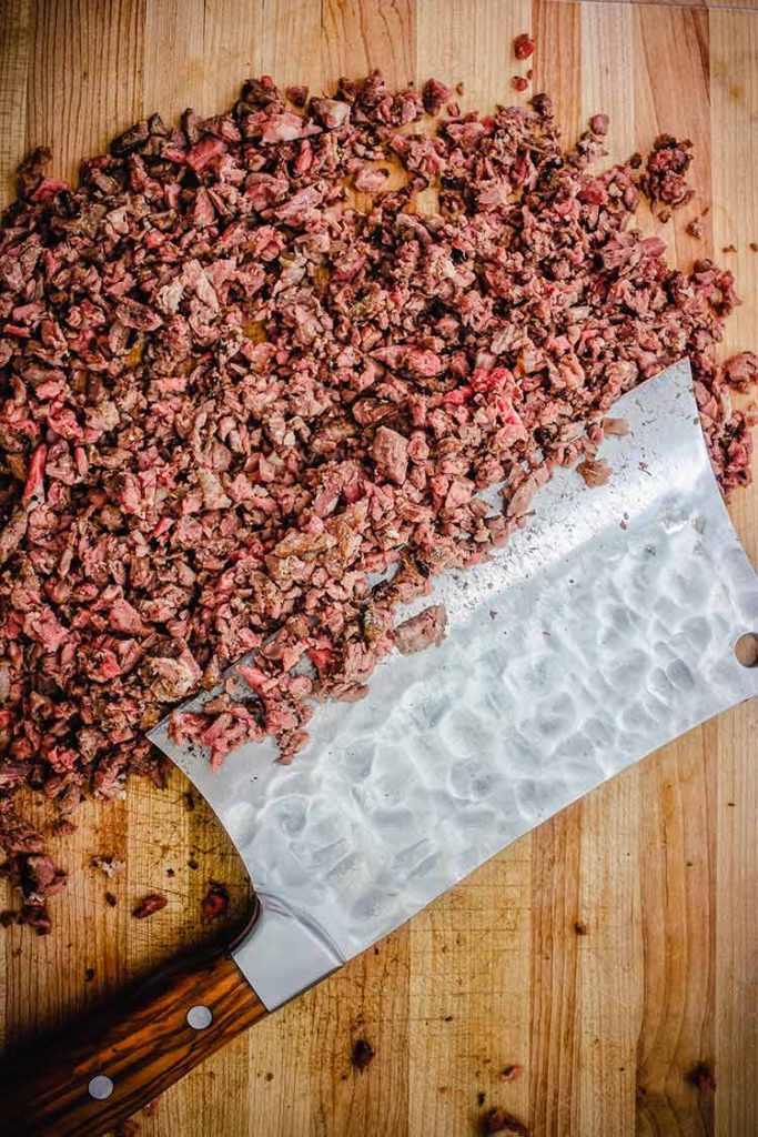 Cleaver chopping steak for Philly Cheesesteak Sliders