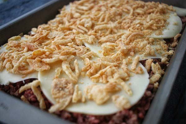 Provolone cheese acting as a barrier to keep fried onions crunchy.