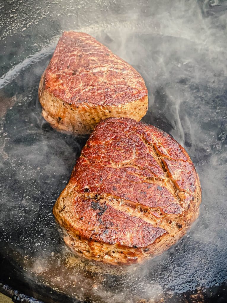 filet mignon searing in a cast iron pan.
