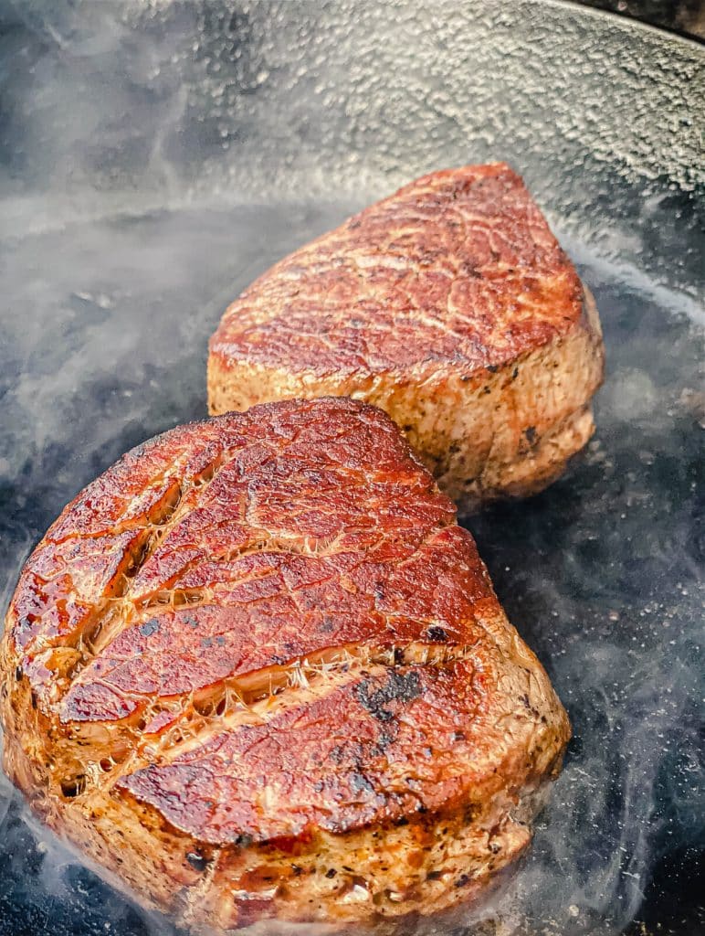 filet mignon searing in a hot cast iron pan