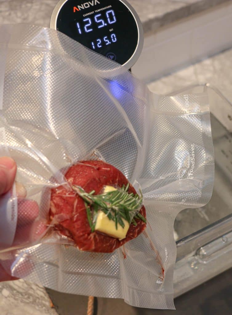 sealed filet mignon being dropped into a sous vide bath