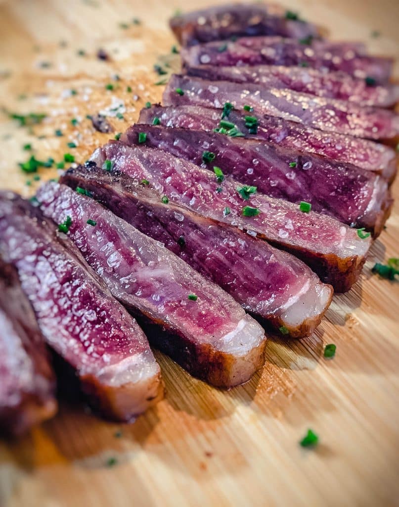 medium rare wagyu strip steak sliced on cutting board