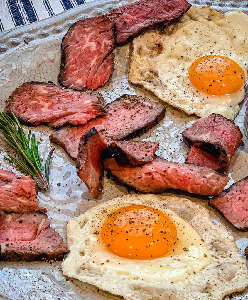 steak and eggs on a platter with rosemary