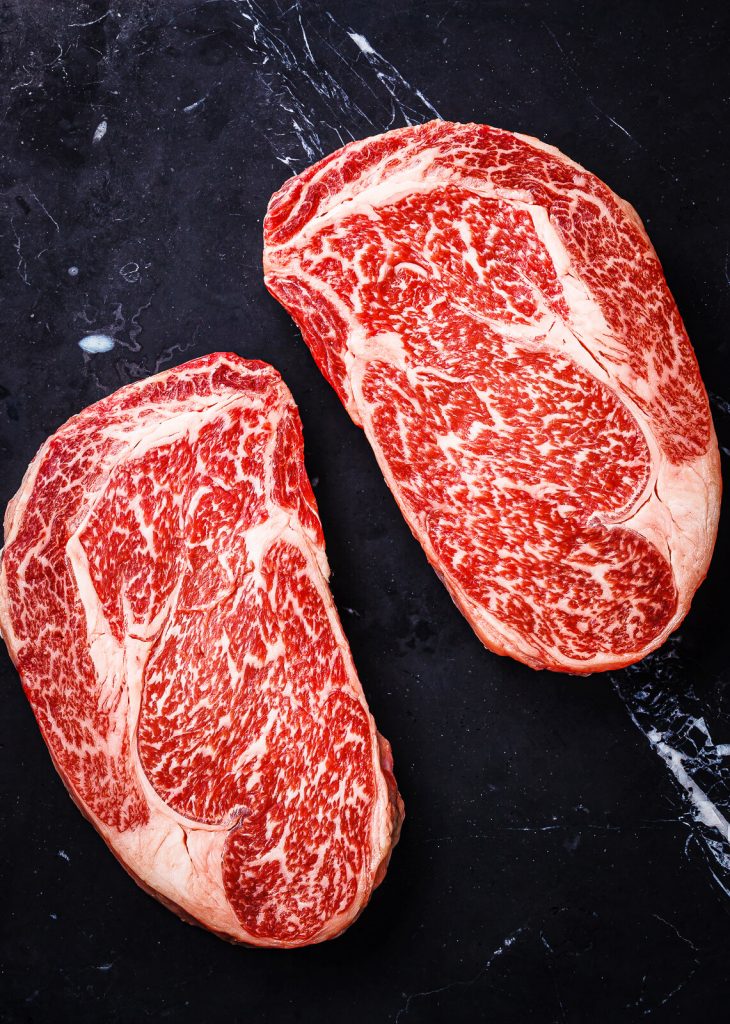 two wagyu ribeye steaks on a slate board