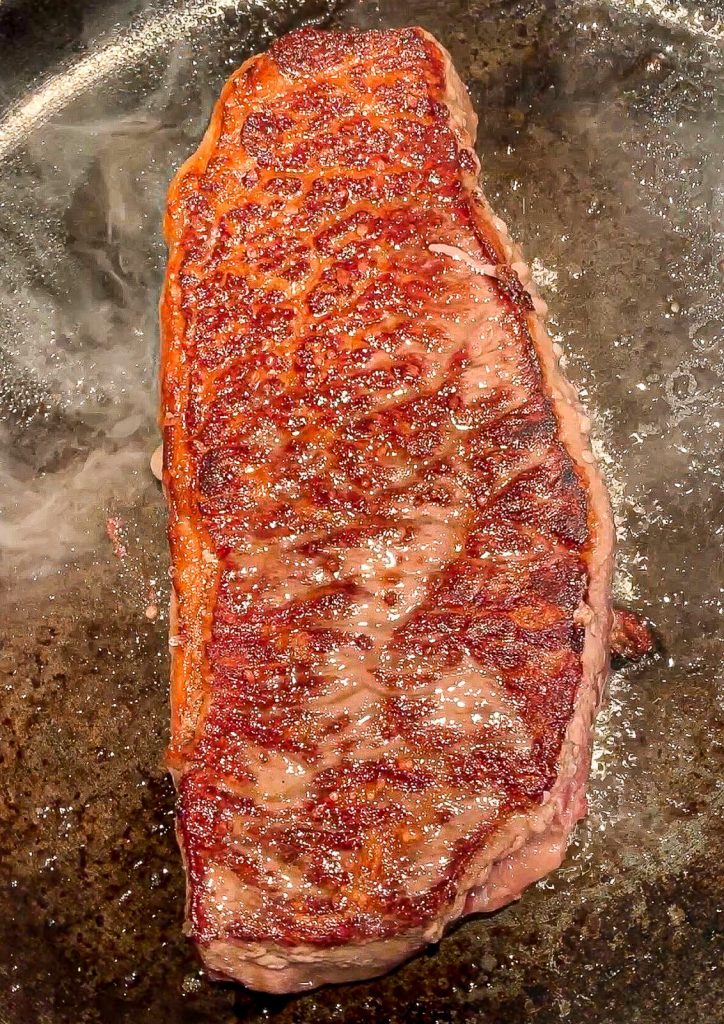 wagyu steak flipped in a cast iron pan