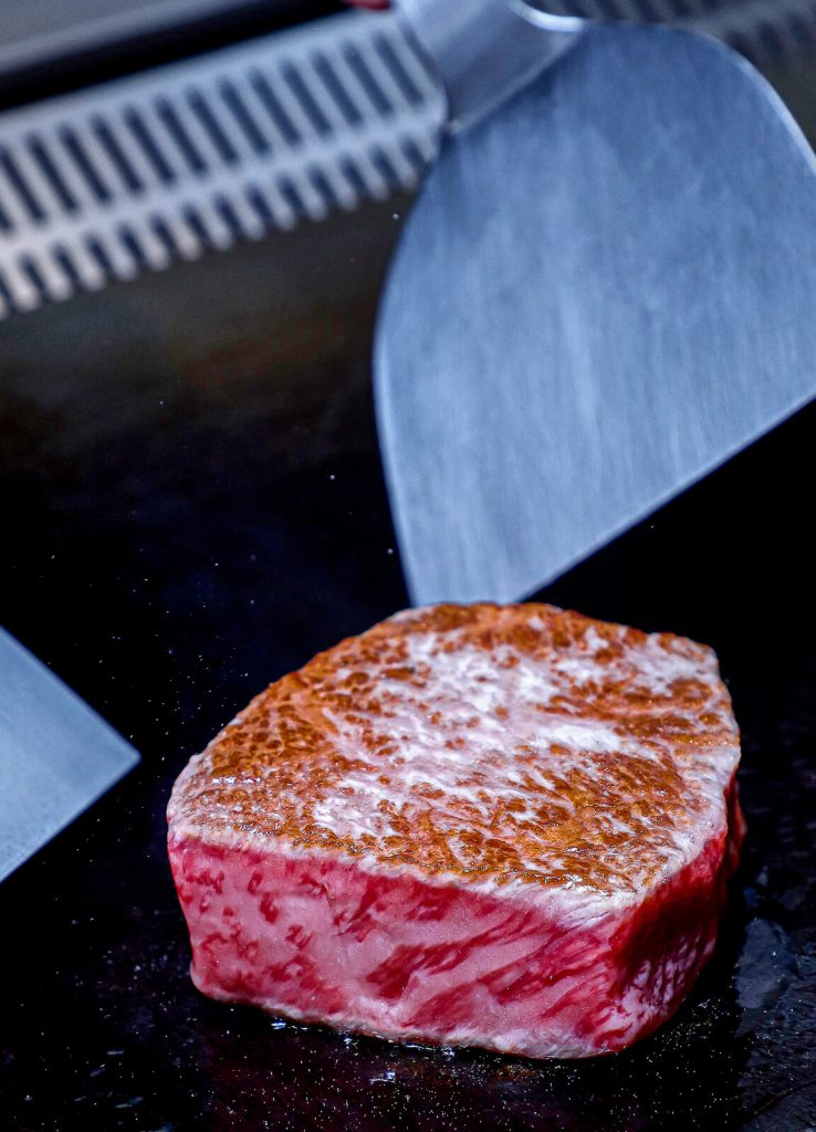 wagyu steak being cooked on a griddle surface