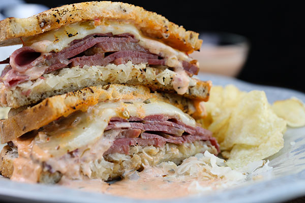 Sliced Reuben sandwich, ready to eat and served with chips