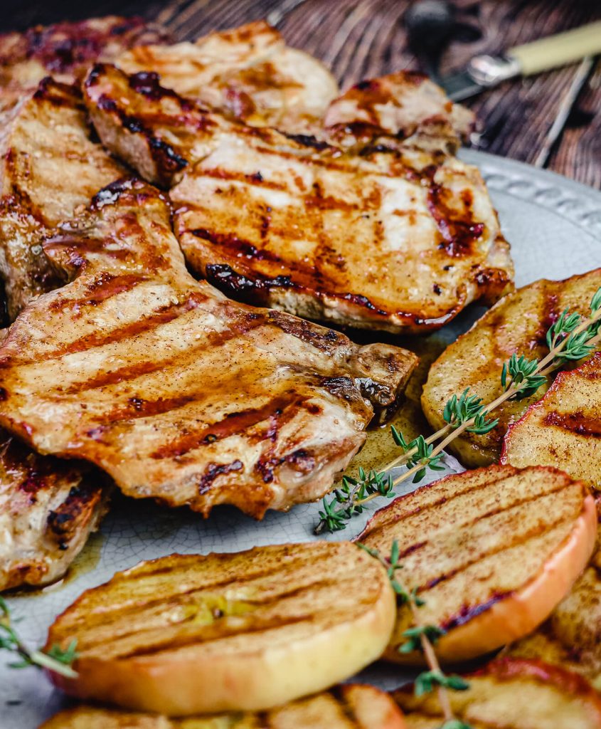 grilled pork chops and apples on a platter with thyme