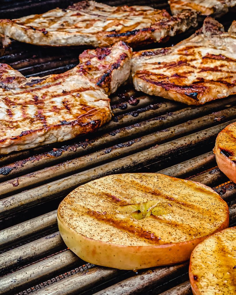 grilled pork chops and apples on a grill