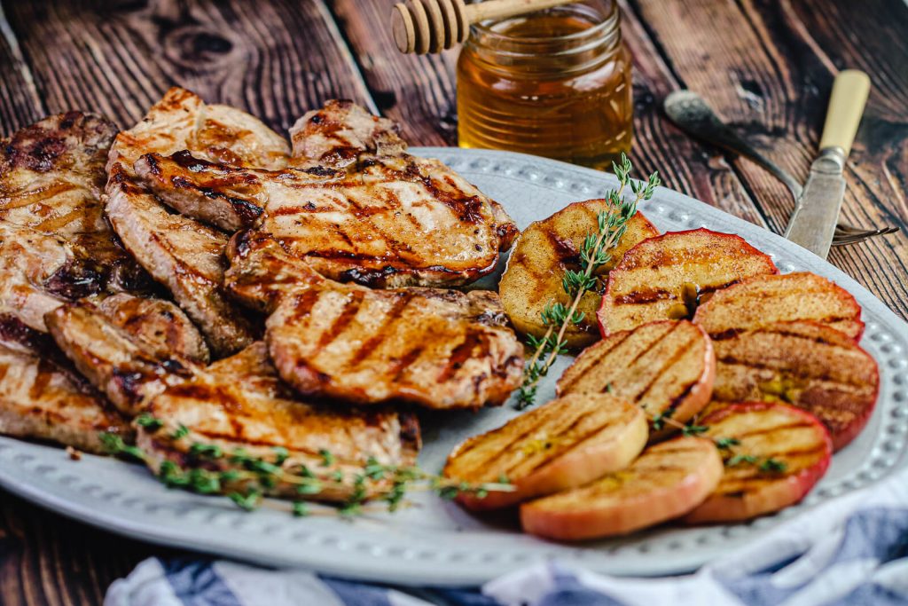 glazed grilled pork chops with cinnamon apples on a platter with honey in the background