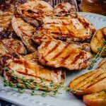 grilled pork chops on a platter with grilled apples