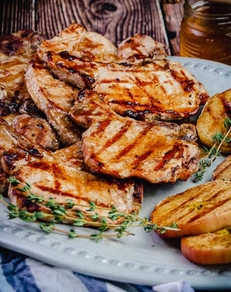 grilled pork chops on a platter with grilled apples