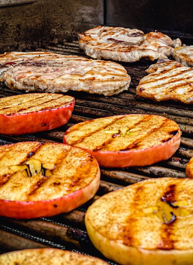 grilled apples on a grill with grilled pork chops in the background