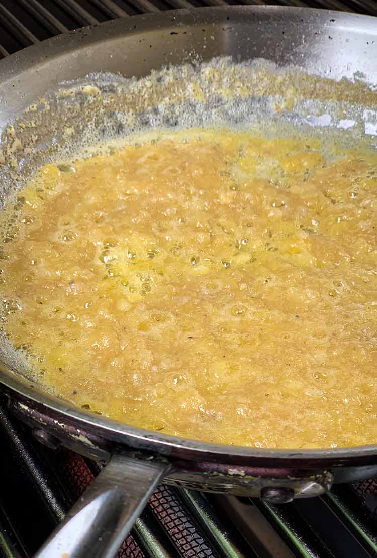 Garlic, white wine, shallots, and butter cooking in a frying pan for the Veal Piccata recipe