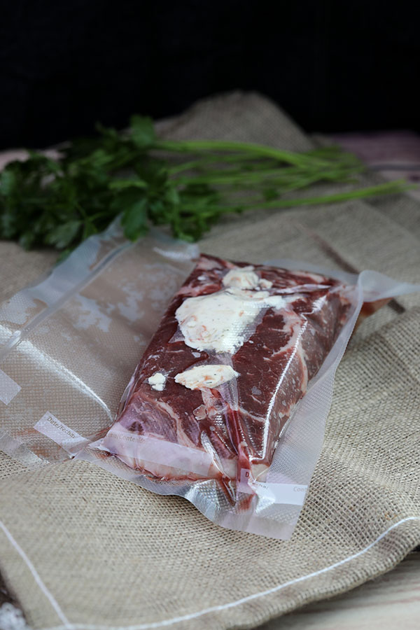 NY strip steak sealed in vacuum bag with compound herb butter