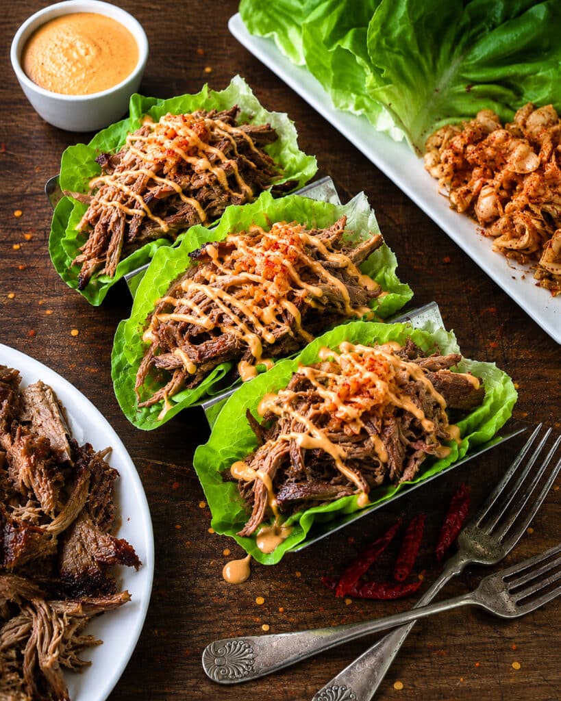 korean pulled pork lettuce wraps on a platter with forks and kimchi