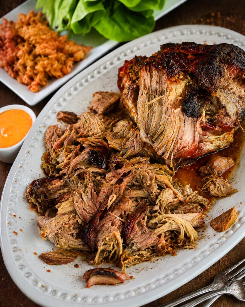 Korean pulled pork on a platter with a side dish of aioli and kimchi
