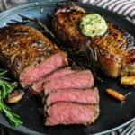 sliced new york strip steaks with compound butter, garlic, and rosemary