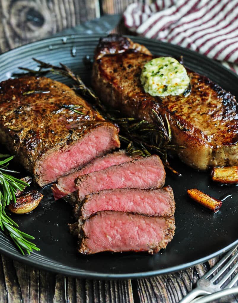 sliced new york strip steaks with compound butter, garlic, and rosemary