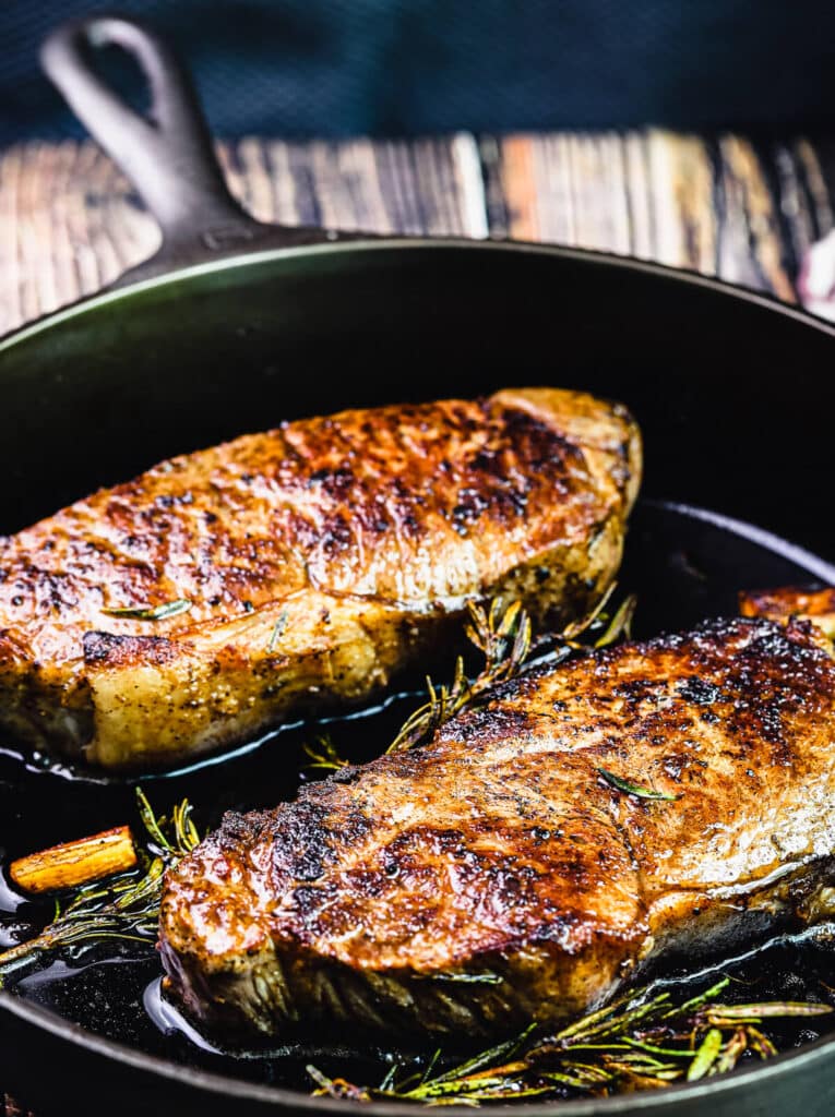 two new york strip steaks in a cast iron pan