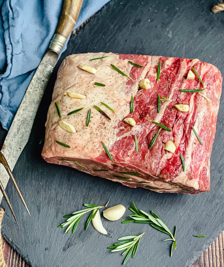 garlic studded roast beef on a cutting board