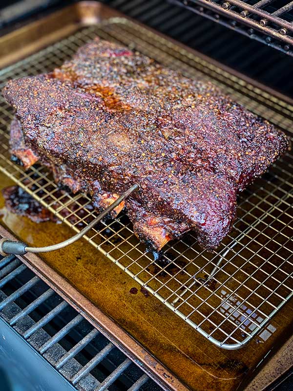Beef ribs on a grill with an internal thermometer
