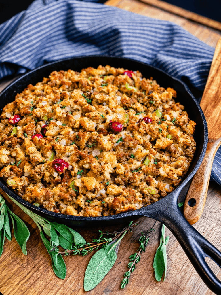 cranberry and sausage stuffing in a cast iron pan with fresh herbs