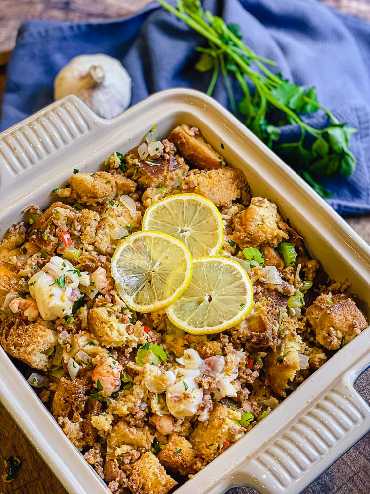 lobster and chorizo stuffing in a ceramic baking dish with garlic in the background