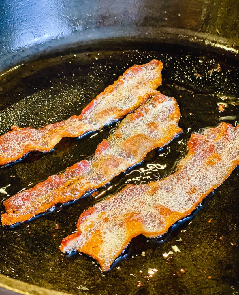 bacon frying in cast iron pan