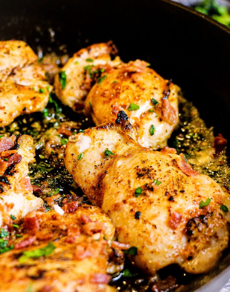 chicken thighs cooking in a cast iron pan