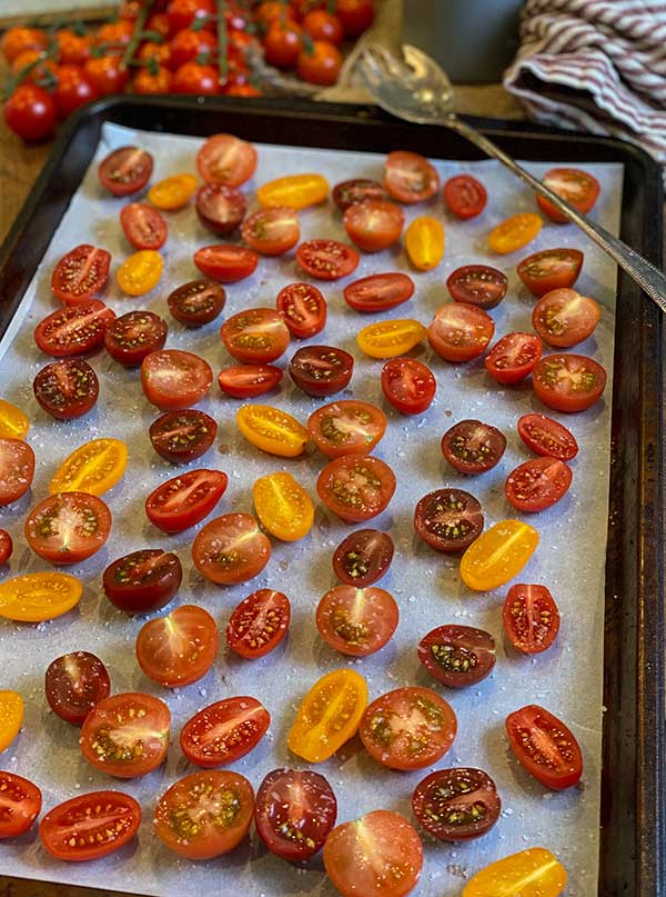 Fresh cherry and grape tomatoes sliced and placed on a baking sheet