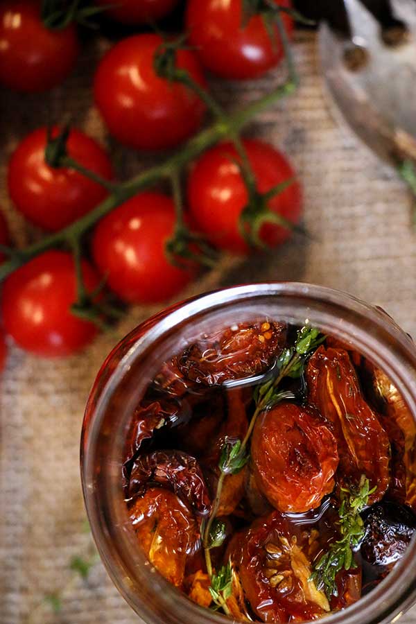 Roasted tomatoes are placed in a glass jar or freezer bag and covered with olive oil.