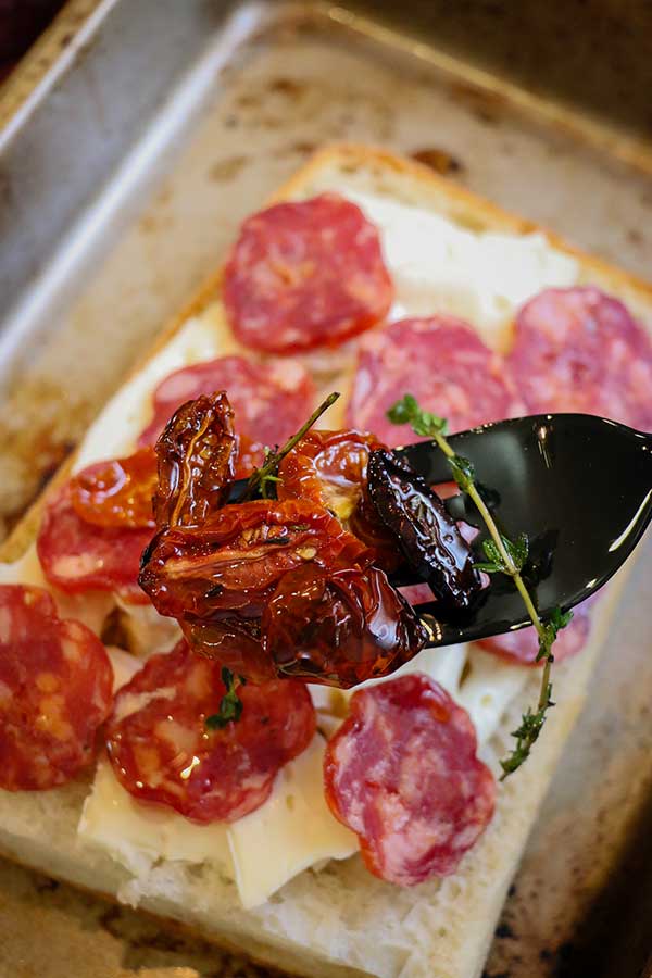 brie and spicy salami on ciabatta placed on baking dish