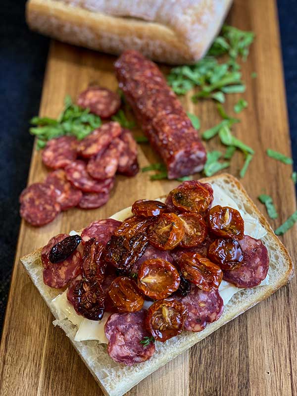 brie and spicy salami on ciabatta placed on baking dish