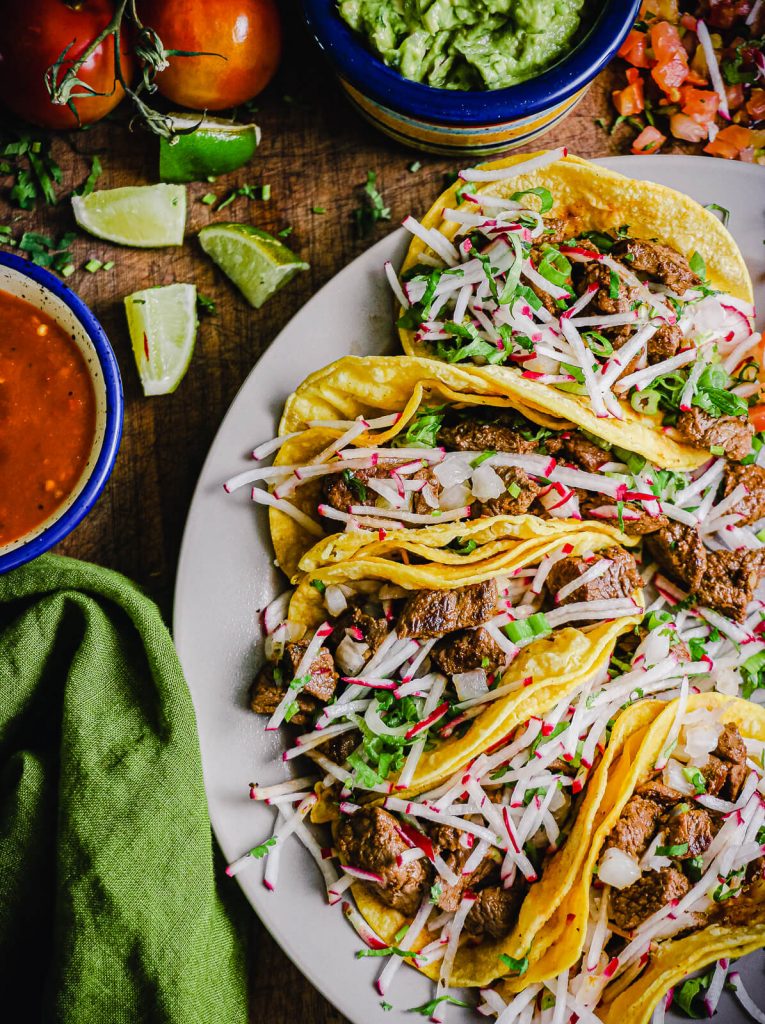 plate of Mexican street tacos with limes and salsa